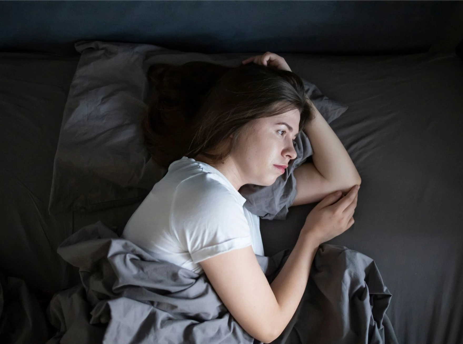 imagen de una madre en la cama pensativa que transmite tristeza ante una pérdida. logo principal Rocío Mesa. Terapéuta emocional y life coach para madres. Presencial y online en Palma de Mallorca